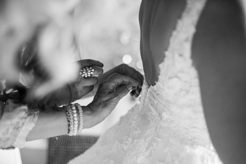 les mains de la maman lacent la robe de la mariée